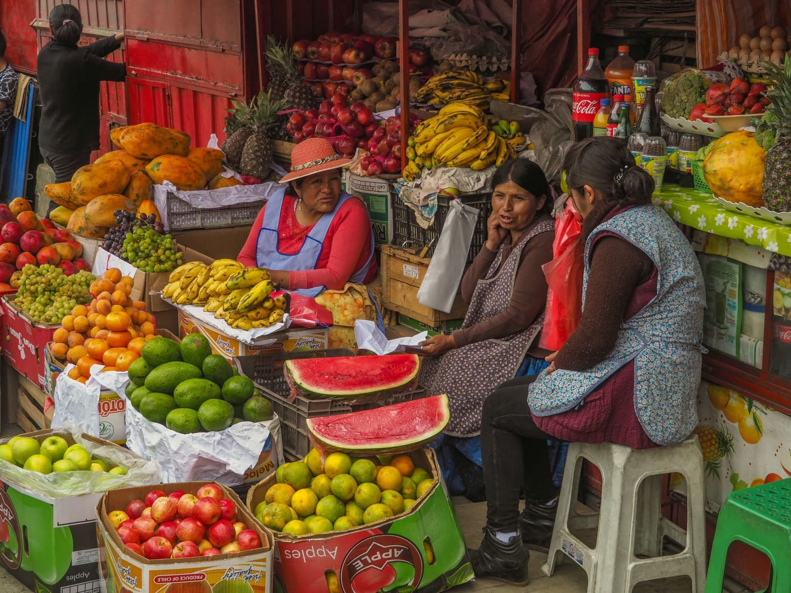 Cholita vendors chatting among the colourful fruit stalls of a Bolivian market