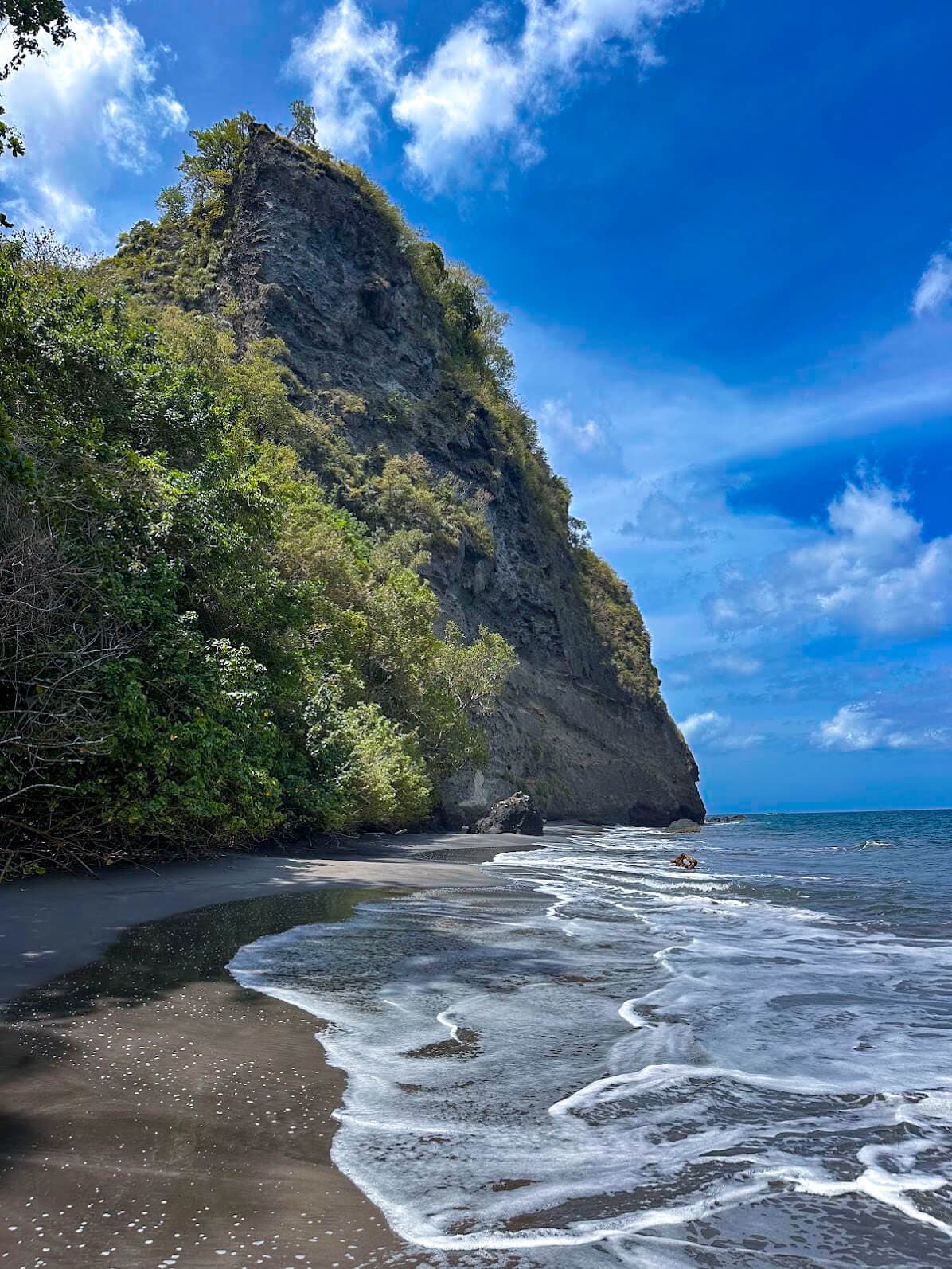Wild Anse Couleuvre beach at the foot of a green cliff in Martinique