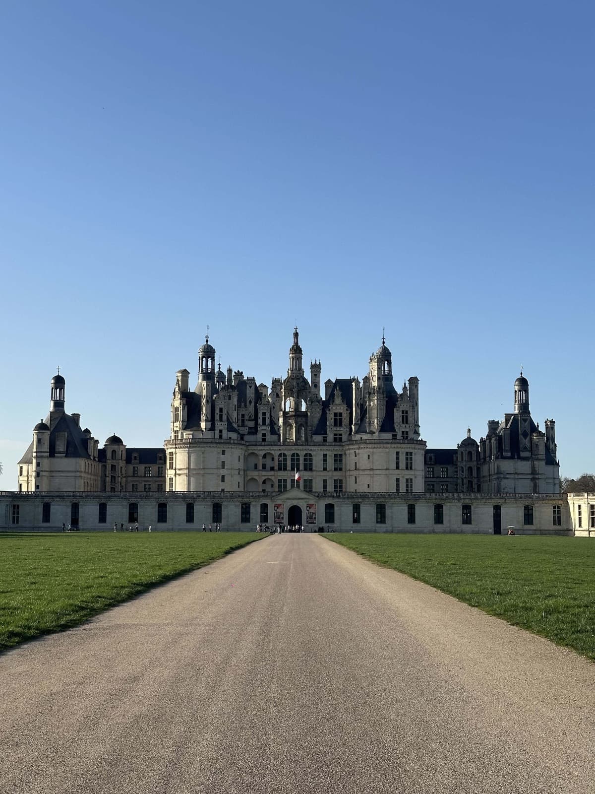 Façade of the Château de Chambord seen from the central path under a blue sky