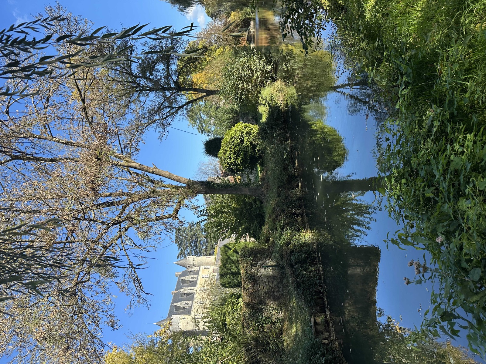 Château de Montrésor se reflétant dans la rivière bordée d'arbres aux couleurs d'automne